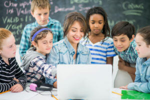 Young students learning a lesson on a computer with their teacher